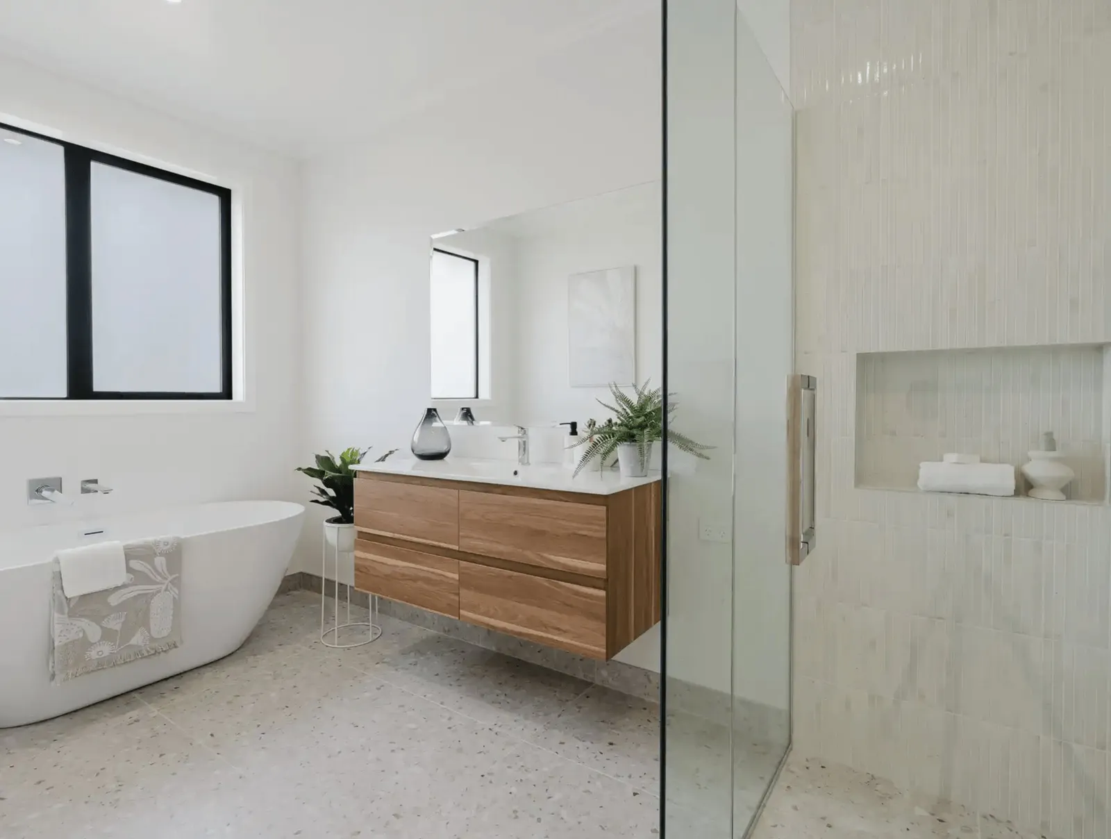 Image of modern neutral bathroom with timber cabinetry, pale grey tiling & glass door shower in Collinson Street, Pirongia new home, by Waikato residential builders Whitechurch Construction Limited.