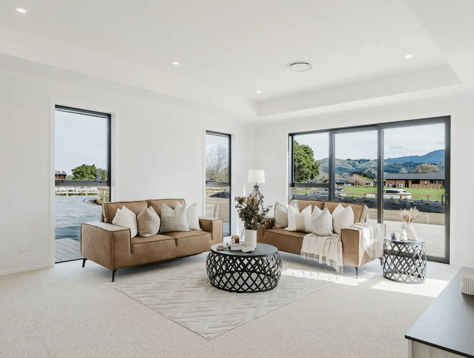 Image of natural light filled lounge with tan lounge suit and modern styling in Collinson Street, Pirongia new home, by Waikato residential builders Whitechurch Construction Limited.