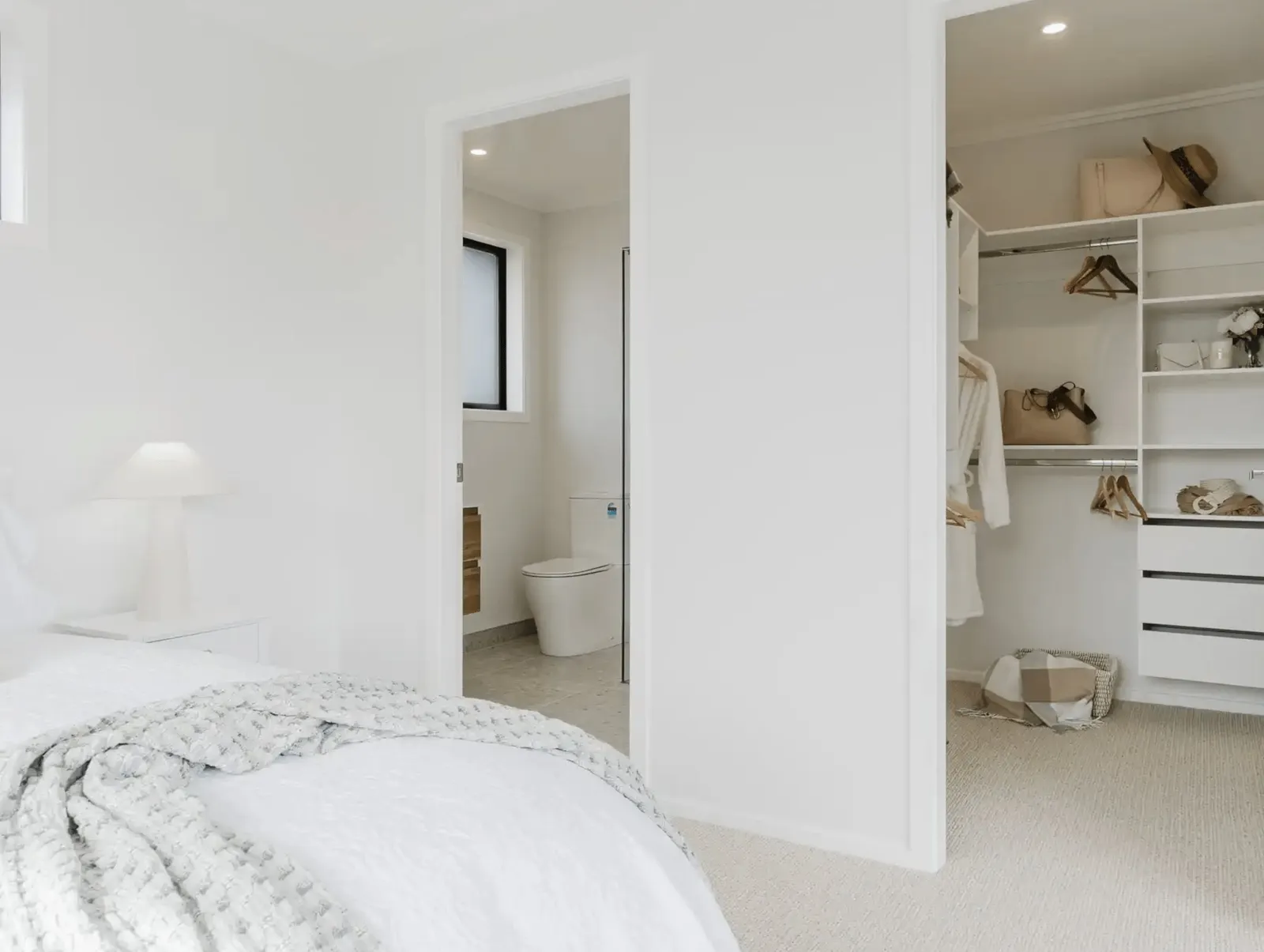 Image of natural light filled master bedroom and glimpse of ensuite and walk in wardrobe in Collinson Street, Pirongia new home, by Waikato residential builders Whitechurch Construction Limited.