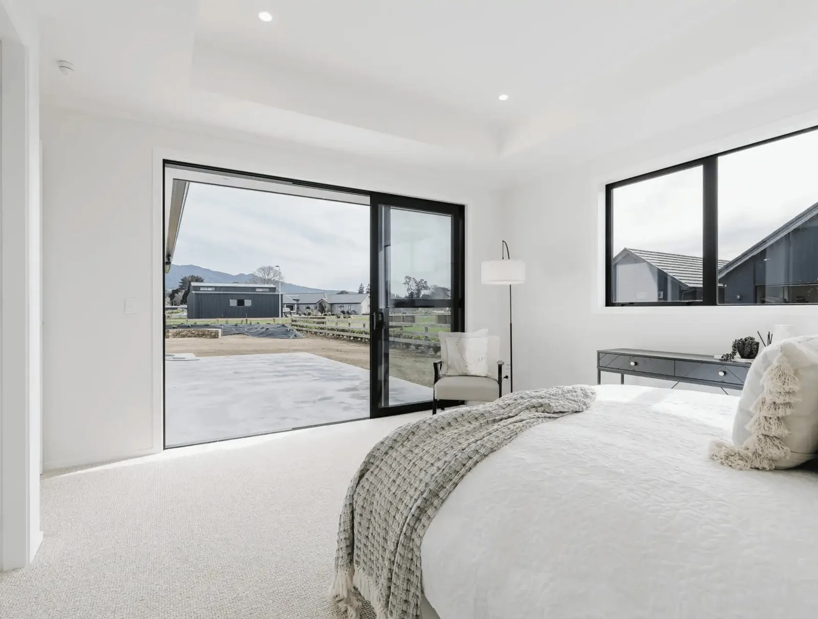 Image of natural light filled master bedroom with neutral styling opening with outlooks in Collinson Street, Pirongia new home, by Waikato residential builders Whitechurch Construction Limited.