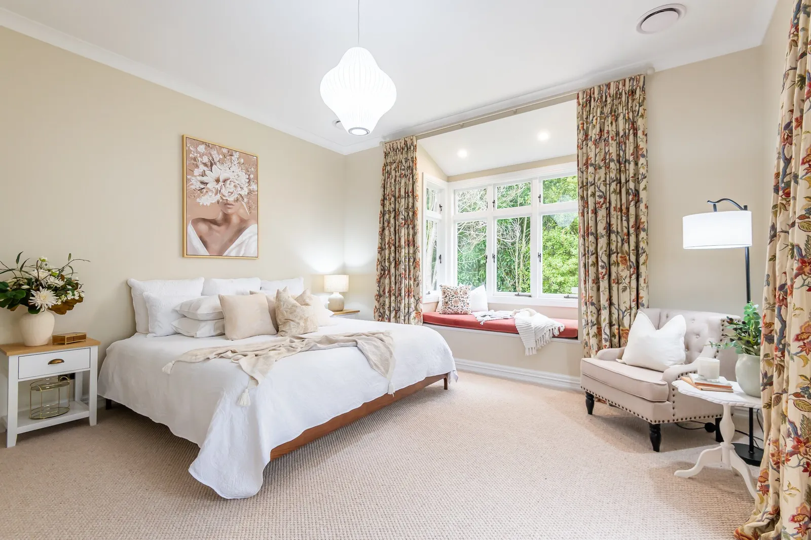 Image of newly renovated master bedroom in sand with floral print curtains and window seat. Renovated by local Te Awamutu residential builders, Whitechurch Construction.