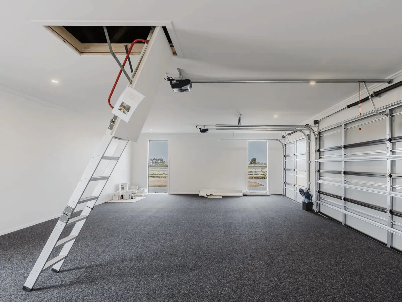Image of fresh white garage with grey carpet and ceiling access in Collinson Street, Pirongia new home, by Waikato residential builders Whitechurch Construction Limited.
