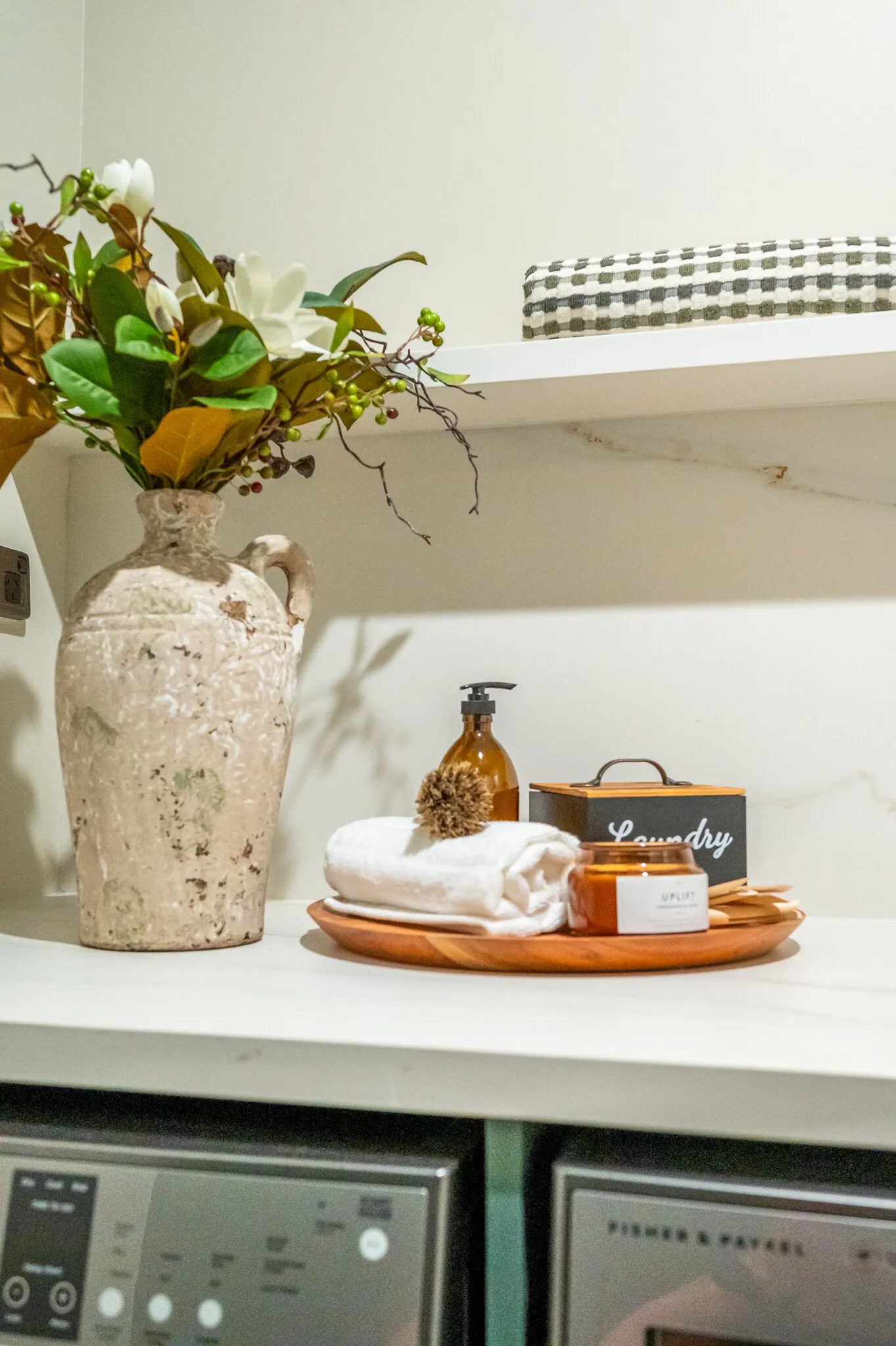 Close up image of laundry accessories and foliage in newly renovated heritage laundry room in deep sage & white. Renovated by local Te Awamutu residential builders, Whitechurch Construction.
